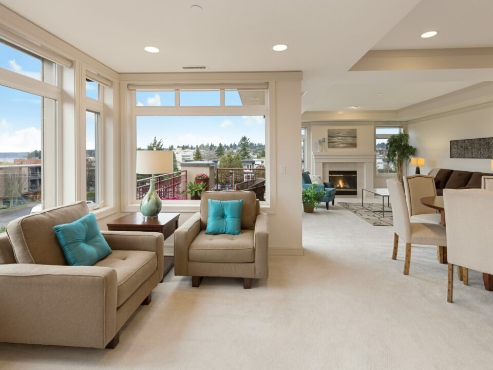 A real estate image of a room with beige sofas and chairs.